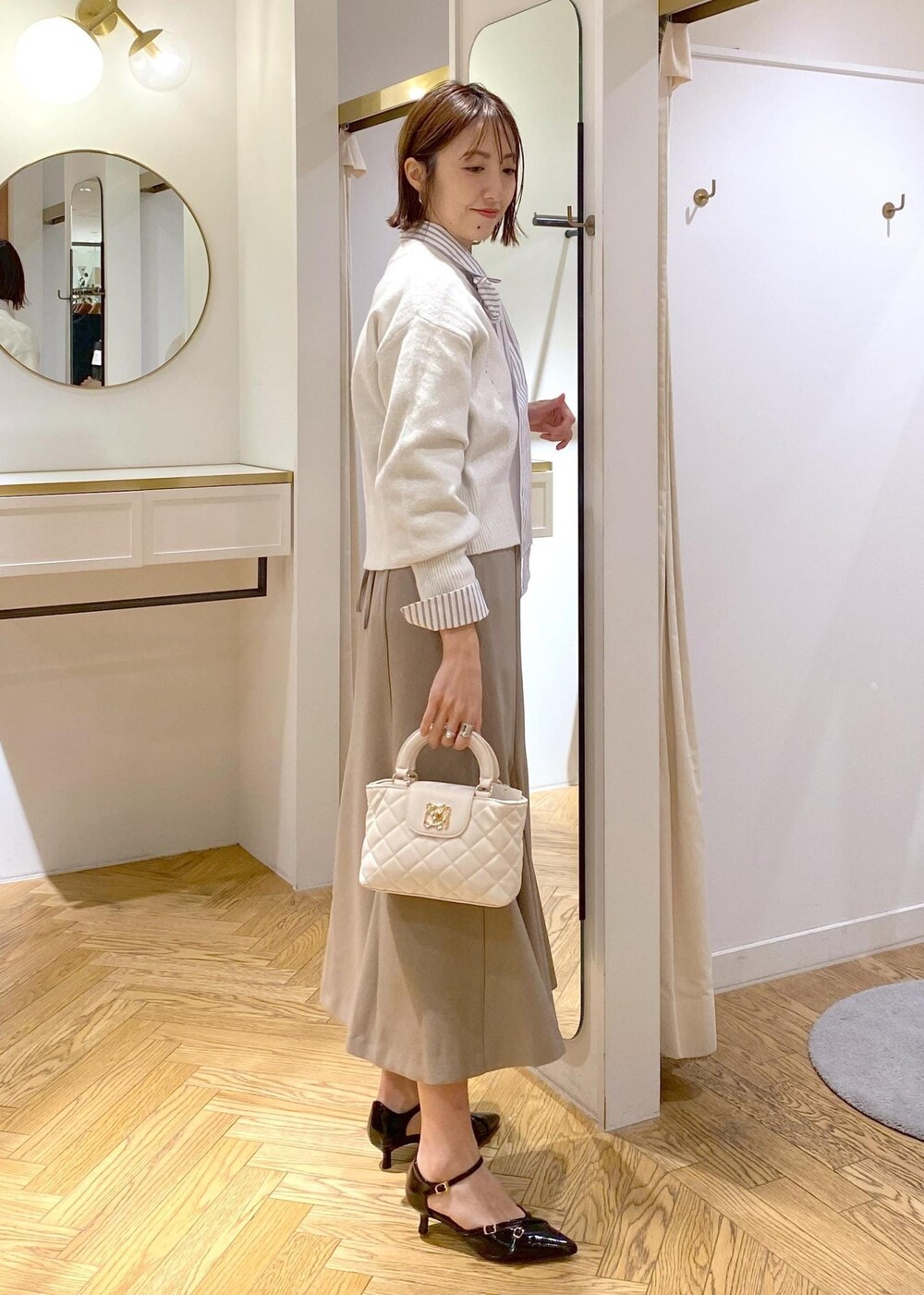 ブラック系のパンプス、ベージュ系のスカート、ホワイト系のシャツ/ブラウスを着用したレディースの冬コーディネートの4枚目の写真