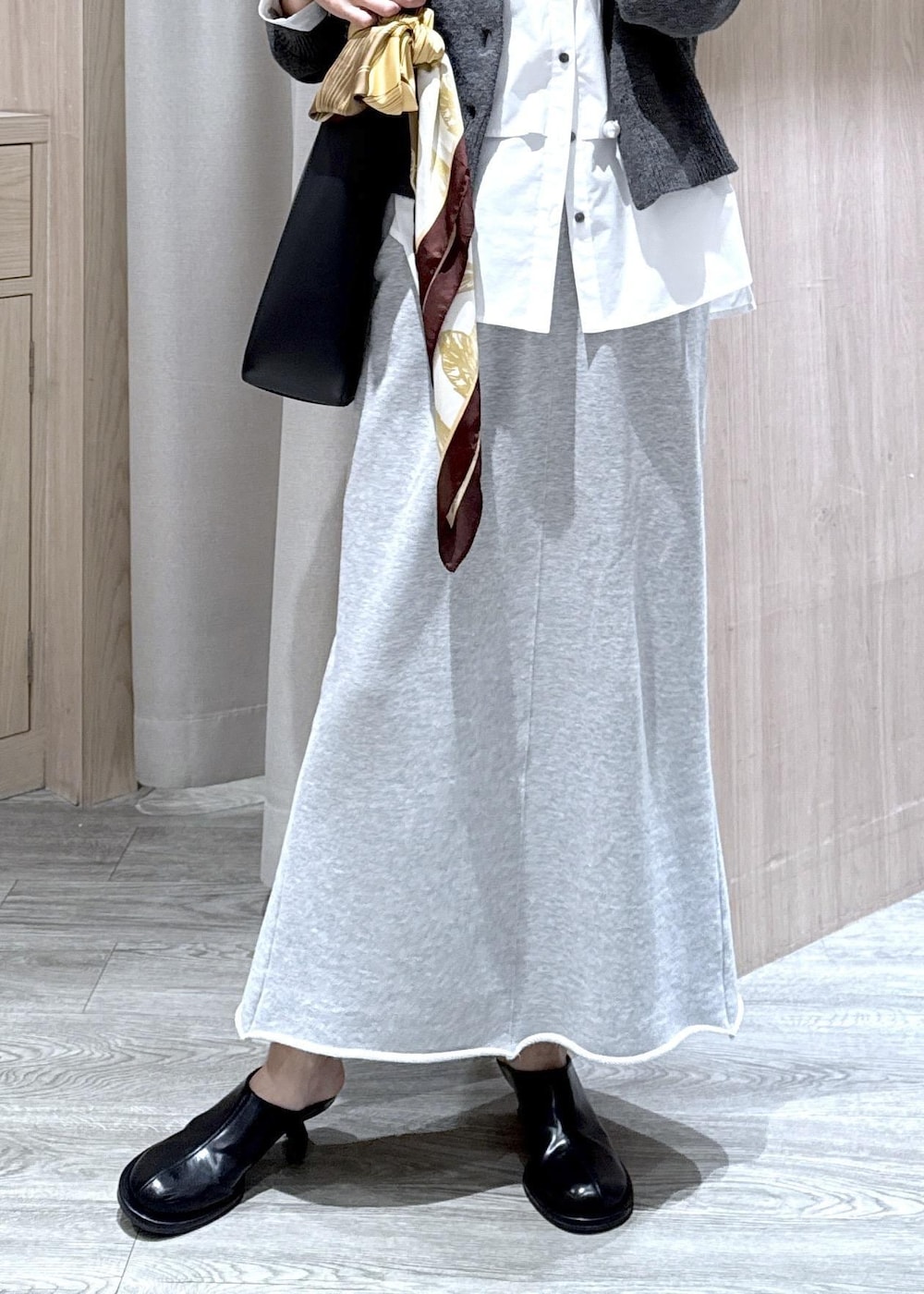 ブラック系のトートバッグ、グレー系のスカート、ホワイト系のシャツ/ブラウスを着用したレディースの秋コーディネートの7枚目の写真