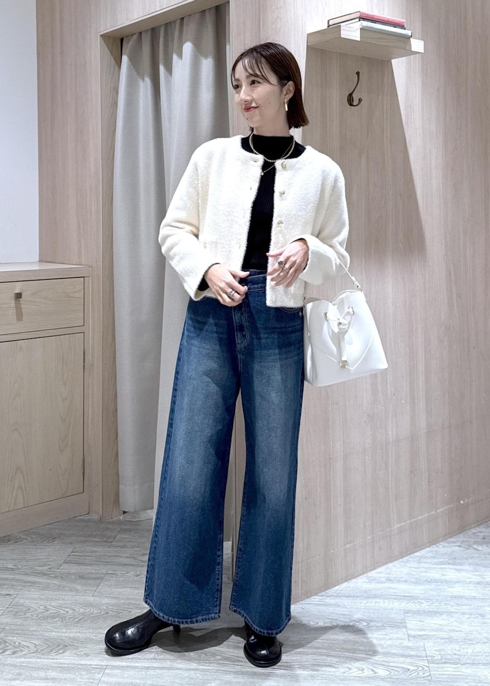 ホワイト系のショルダーバッグ、ブルー系のデニムパンツ、ブラック系のニット/セーターを着用したレディースの冬コーディネートの9枚目の写真