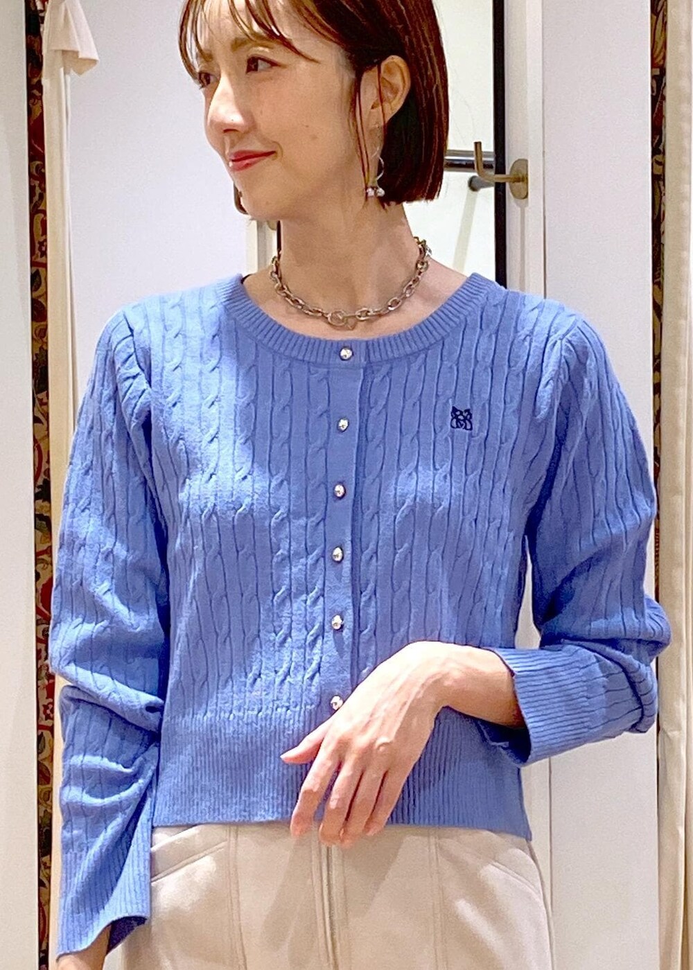 ホワイト系のショルダーバッグ、ブルー系のカーディガン/ボレロ、ベージュ系のスカートを着用したレディースの冬コーディネートの8枚目の写真