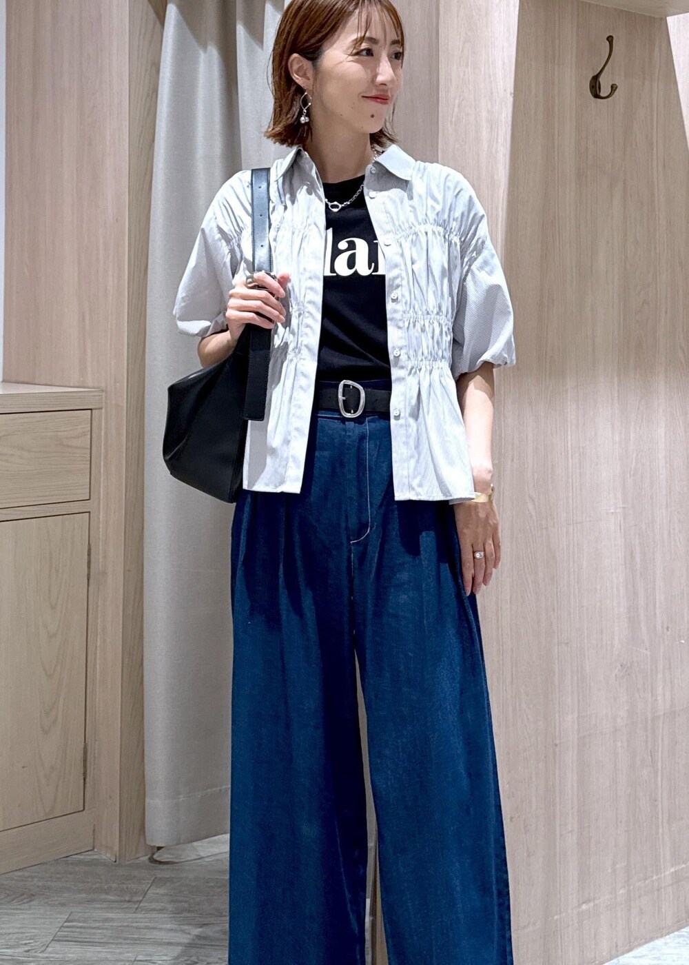 ブラック系のショルダーバッグ、ブラック系のサンダル、ブルー系のデニムパンツを着用したレディースの夏コーディネートの6枚目の写真