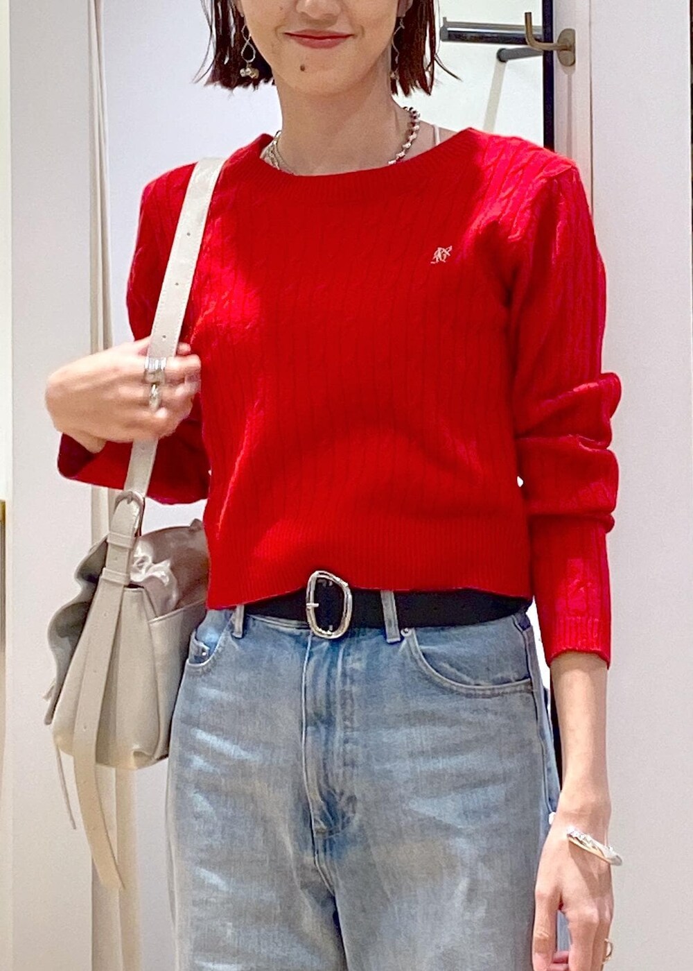 レッド系のニット/セーター、ブルー系のデニムパンツ、ブラック系のベルトを着用したレディースの冬コーディネートの8枚目の写真