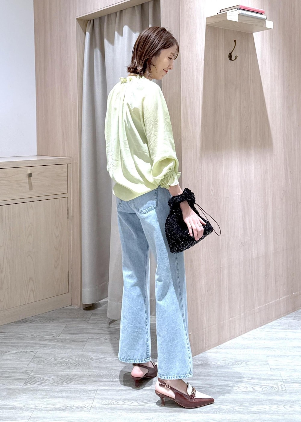 ブルー系のデニムパンツ、ブラウン系のパンプス、ブラック系のハンドバッグを着用したレディースの春コーディネートの4枚目の写真