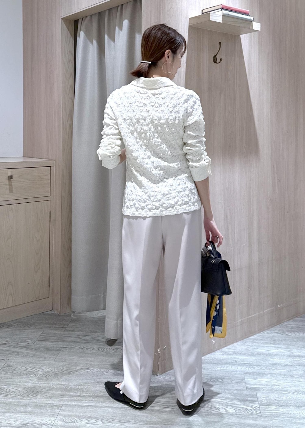 ベージュ系のその他パンツ、ホワイト系のカーディガン/ボレロ、ブラック系のショルダーバッグを着用したレディースの春コーディネートの2枚目の写真