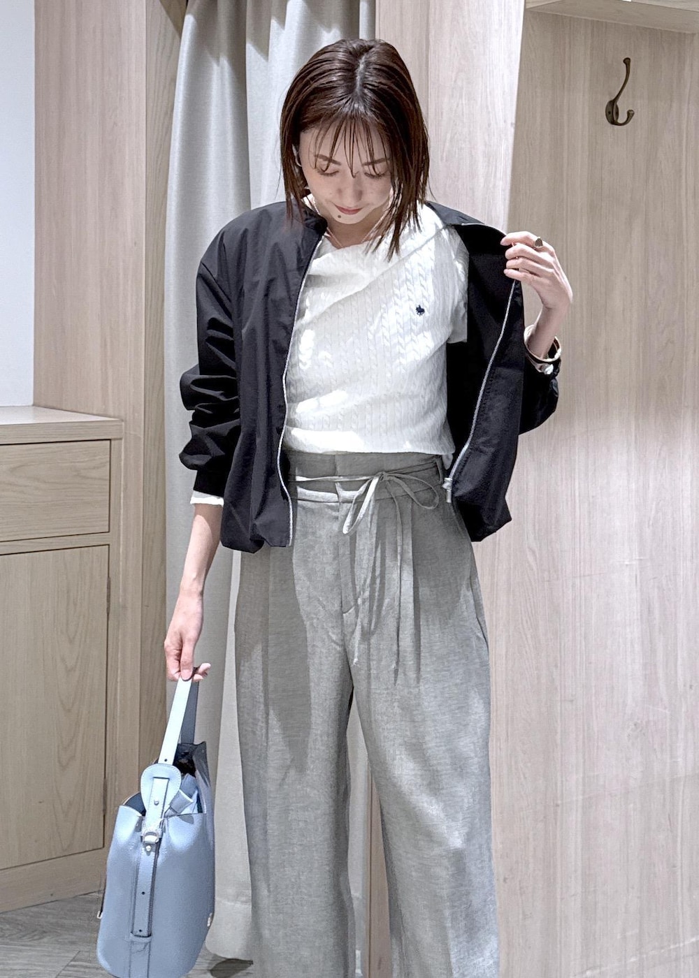 ブルー系のショルダーバッグ、ホワイト系のパンプス、ブラック系のブルゾンを着用したレディースの春コーディネートの5枚目の写真