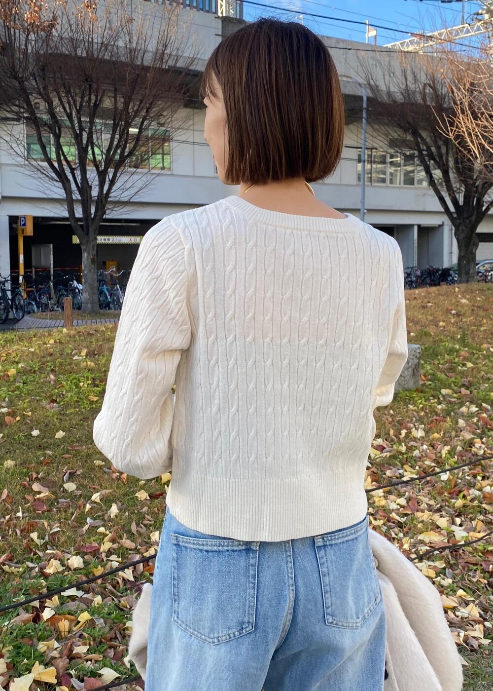 ブラック系のパンプス、ホワイト系のカーディガン/ボレロ、ベージュ系のその他アウターを着用したレディースの冬コーディネートの6枚目の写真