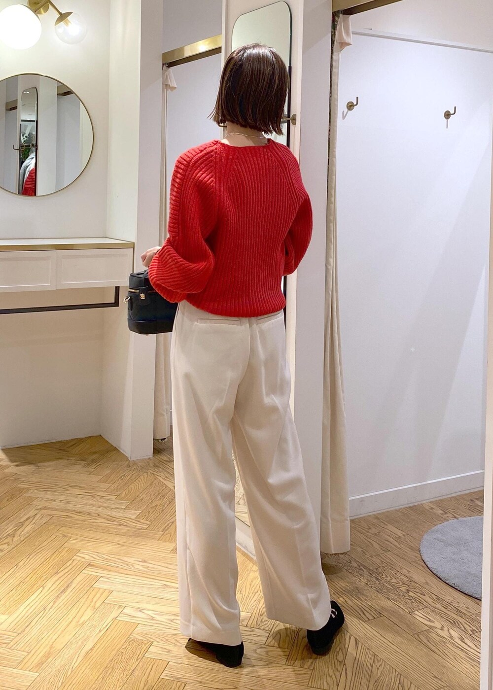 レッド系のニット/セーター、ホワイト系のスラックス、ブラック系のハンドバッグを着用したレディースの冬コーディネートの3枚目の写真