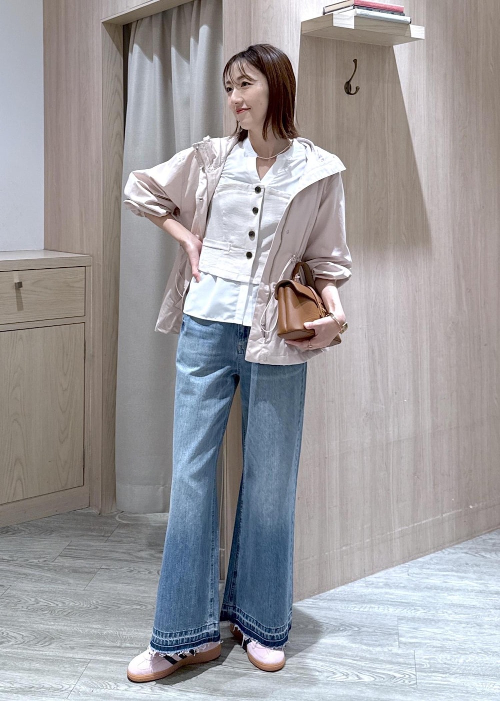 イエロー系のショルダーバッグ、ピンク系のナイロンジャケット、ブルー系のデニムパンツを着用したレディースの春コーディネートの2枚目の写真