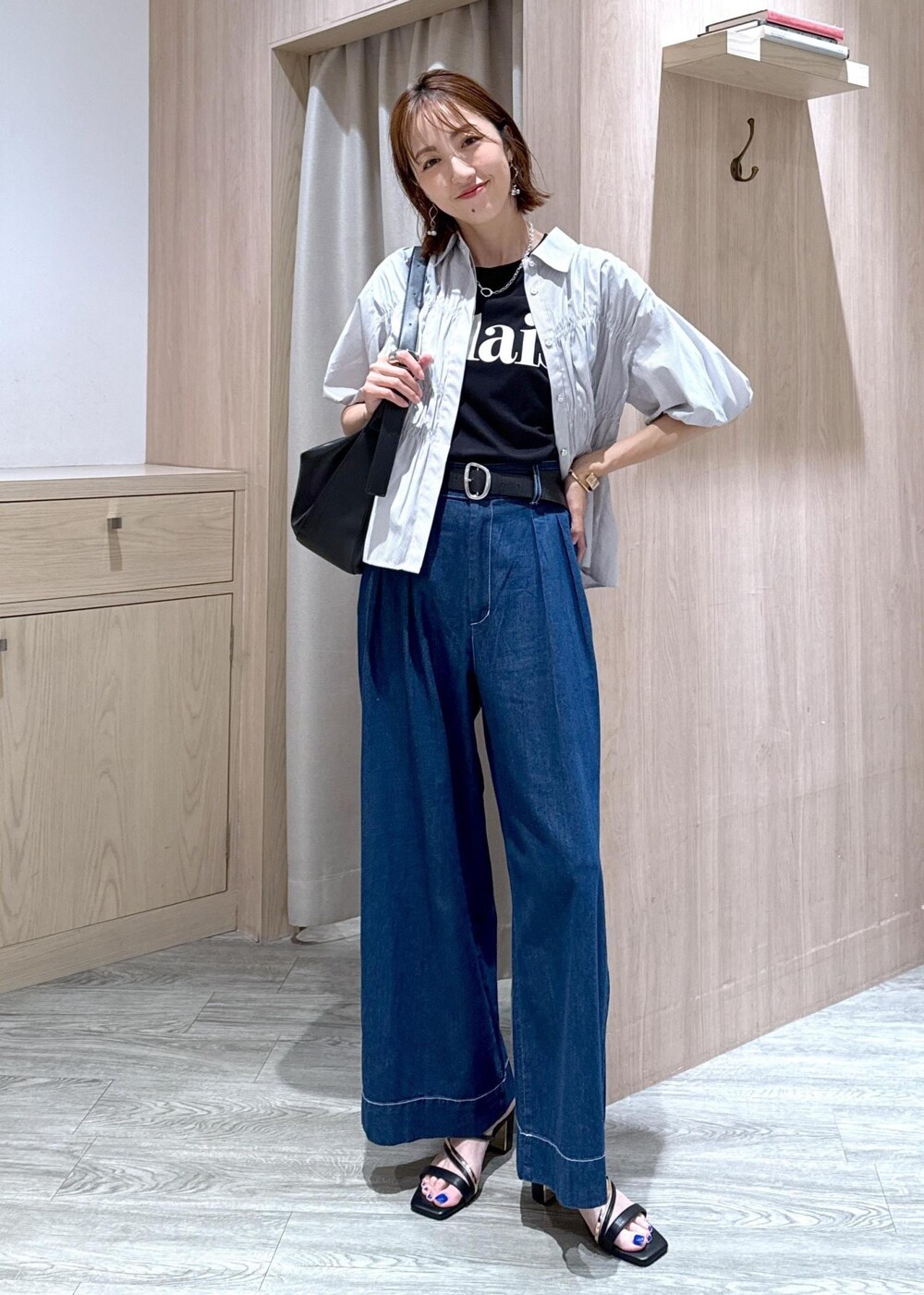 ブラック系のショルダーバッグ、ブラック系のサンダル、ブルー系のデニムパンツを着用したレディースの夏コーディネートの2枚目の写真