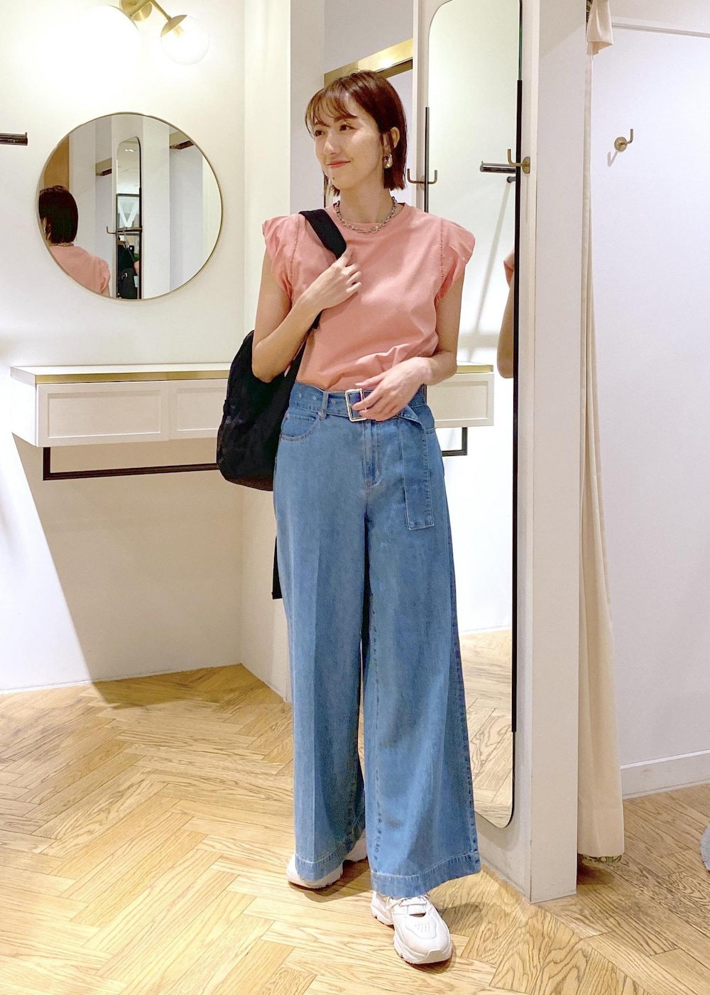 グレー系のスニーカー、ブラック系のバックパック/リュック、ピンク系のTシャツ/カットソーを着用したレディースの春コーディネートの3枚目の写真