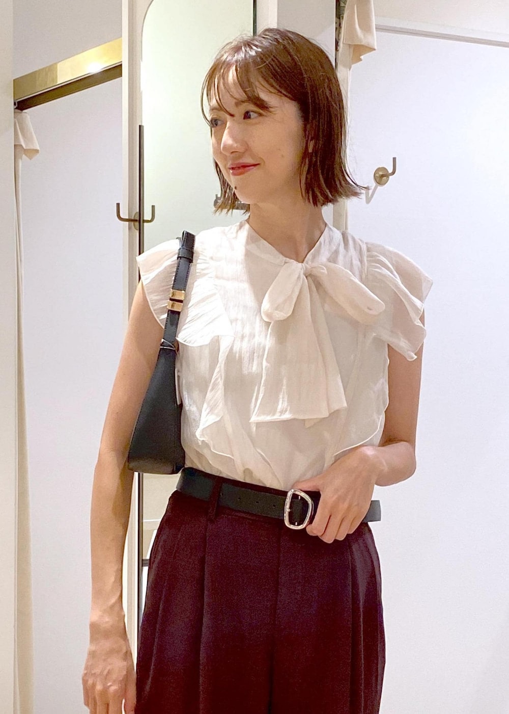 ブラック系のハンドバッグ、ブラック系のパンプス、ブラウン系のスラックスを着用したレディースの夏コーディネートの5枚目の写真