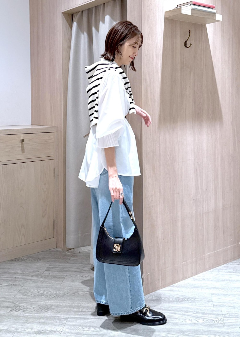 ブラック系のハンドバッグ、ブラック系のローファー、ホワイト系のシャツ/ブラウスを着用したレディースの春コーディネートの2枚目の写真