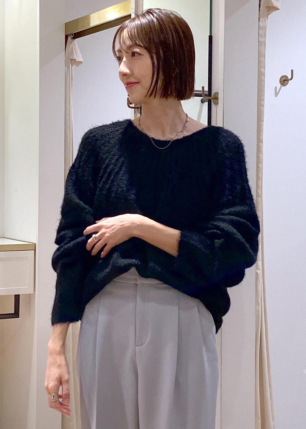 ブルー系のスラックス、ブラック系のパンプス、ブラック系のショルダーバッグを着用したレディースの冬コーディネートの7枚目の写真