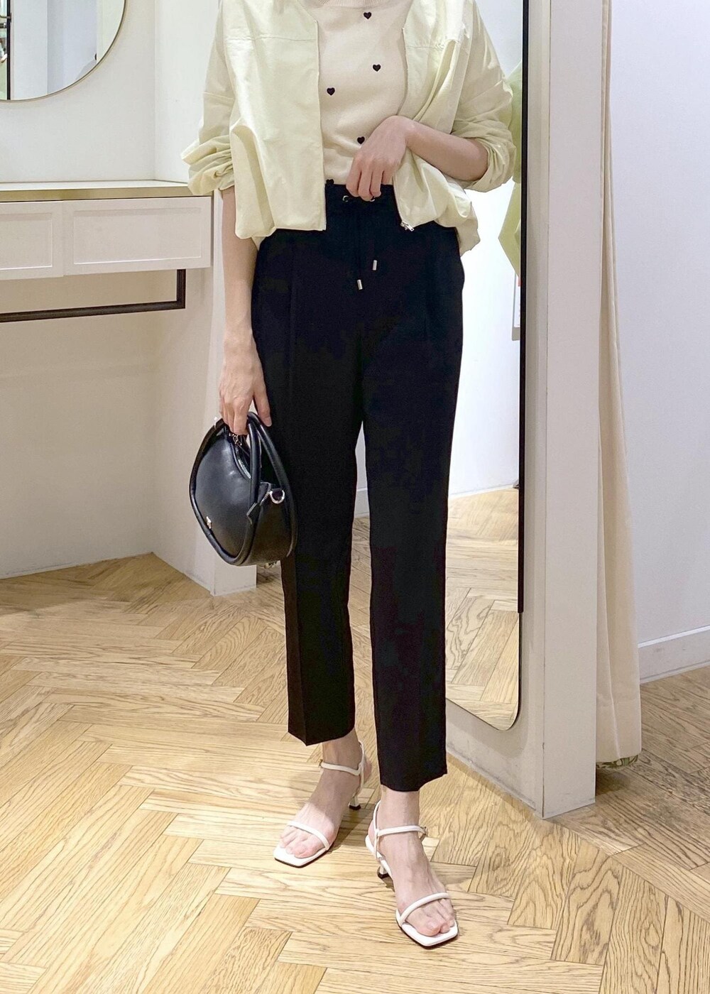ブラック系のショルダーバッグ、ホワイト系のキャミソール、ブラック系のスラックスを着用したレディースの春コーディネートの4枚目の写真