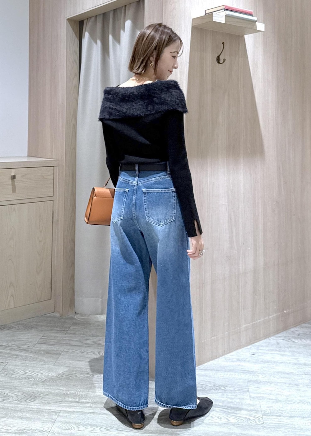 ブルー系のデニムパンツ、イエロー系のハンドバッグ、ブラック系のニット/セーターを着用したレディースの冬コーディネートの4枚目の写真