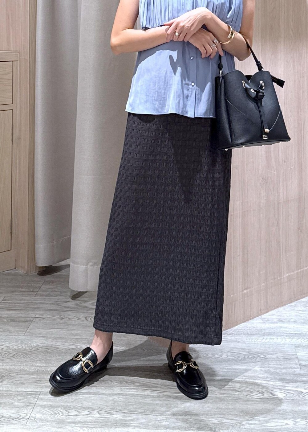 ブラック系のショルダーバッグ、ブラック系のローファー、グレー系のスカートを着用したレディースの夏コーディネートの5枚目の写真