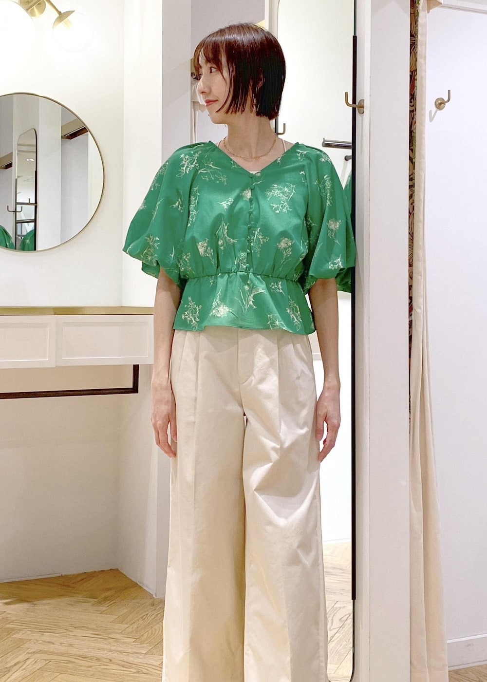 ホワイト系のスラックス、ホワイト系のマウンテンパーカー、ブラック系のサンダルを着用したレディースの春コーディネートの5枚目の写真