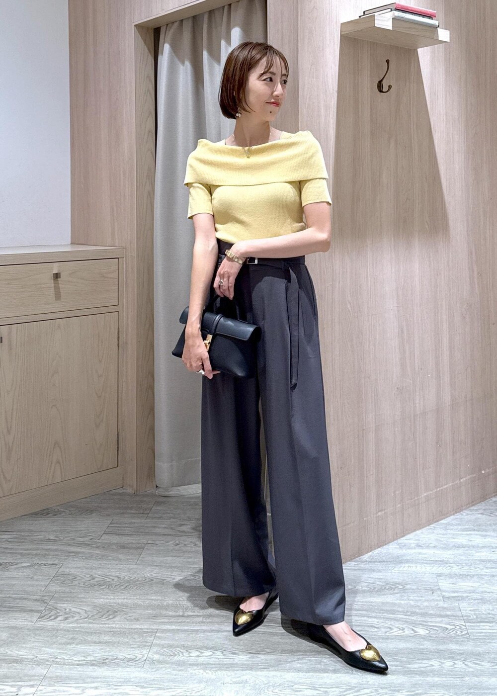 ブラック系のショルダーバッグ、ブラック系のバレエシューズ、イエロー系のニット/セーターを着用したレディースの夏コーディネートの9枚目の写真
