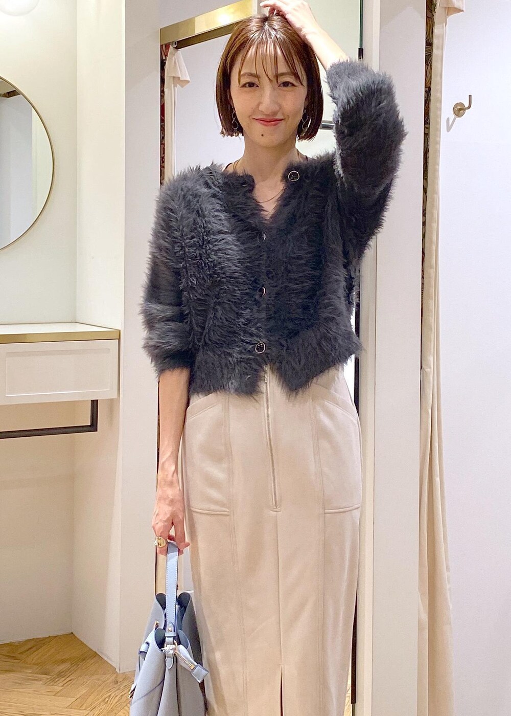 ブラック系のブーツ、ベージュ系のスカート、グレー系のカーディガン/ボレロを着用したレディースの冬コーディネートの6枚目の写真