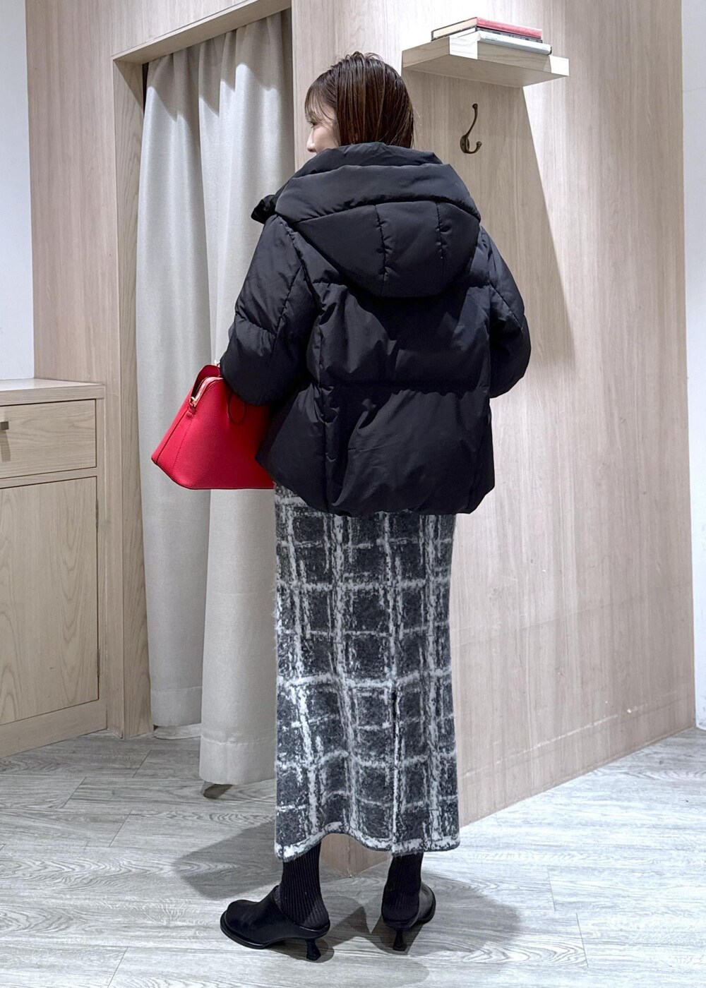 レッド系のボストンバッグ、ブラック系のダウンジャケット/コート、グレー系のスカートを着用したレディースの冬コーディネートの6枚目の写真