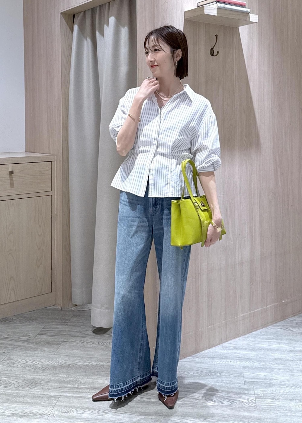ブルー系のデニムパンツ、グリーン系のトートバッグ、ホワイト系のシャツ/ブラウスを着用したレディースの春コーディネートの2枚目の写真