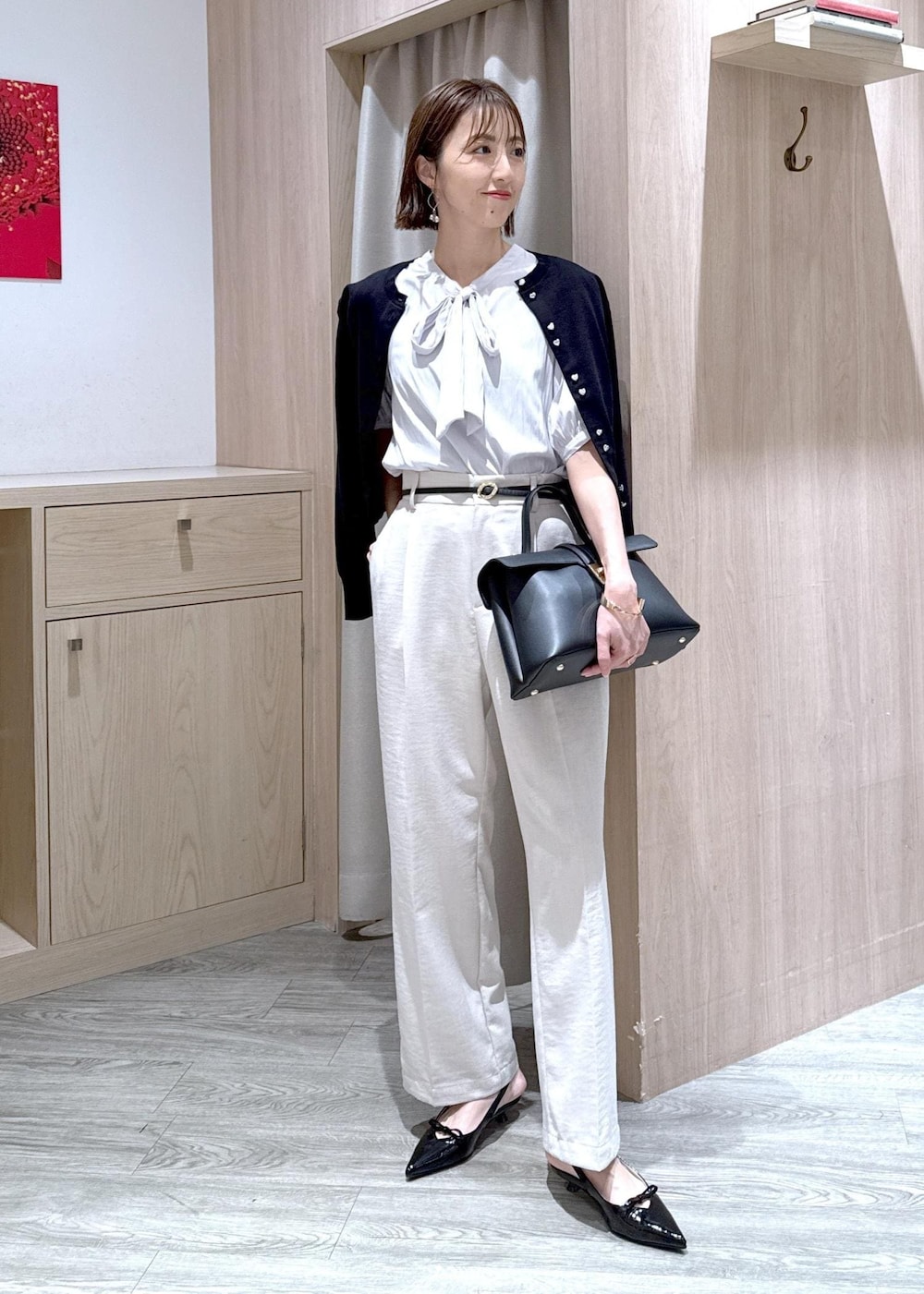 ブラック系のハンドバッグ、ブラック系のカーディガン/ボレロ、ブラック系のパンプスを着用したレディースの春コーディネートの3枚目の写真