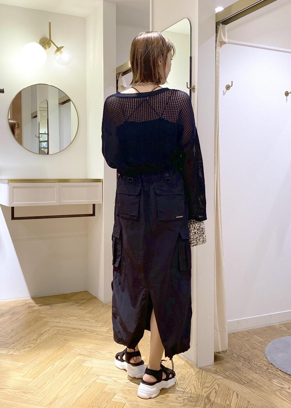 シルバー系のショルダーバッグ、ブラック系のスカート、ブラック系のニット/セーターを着用したレディースの春コーディネートの2枚目の写真