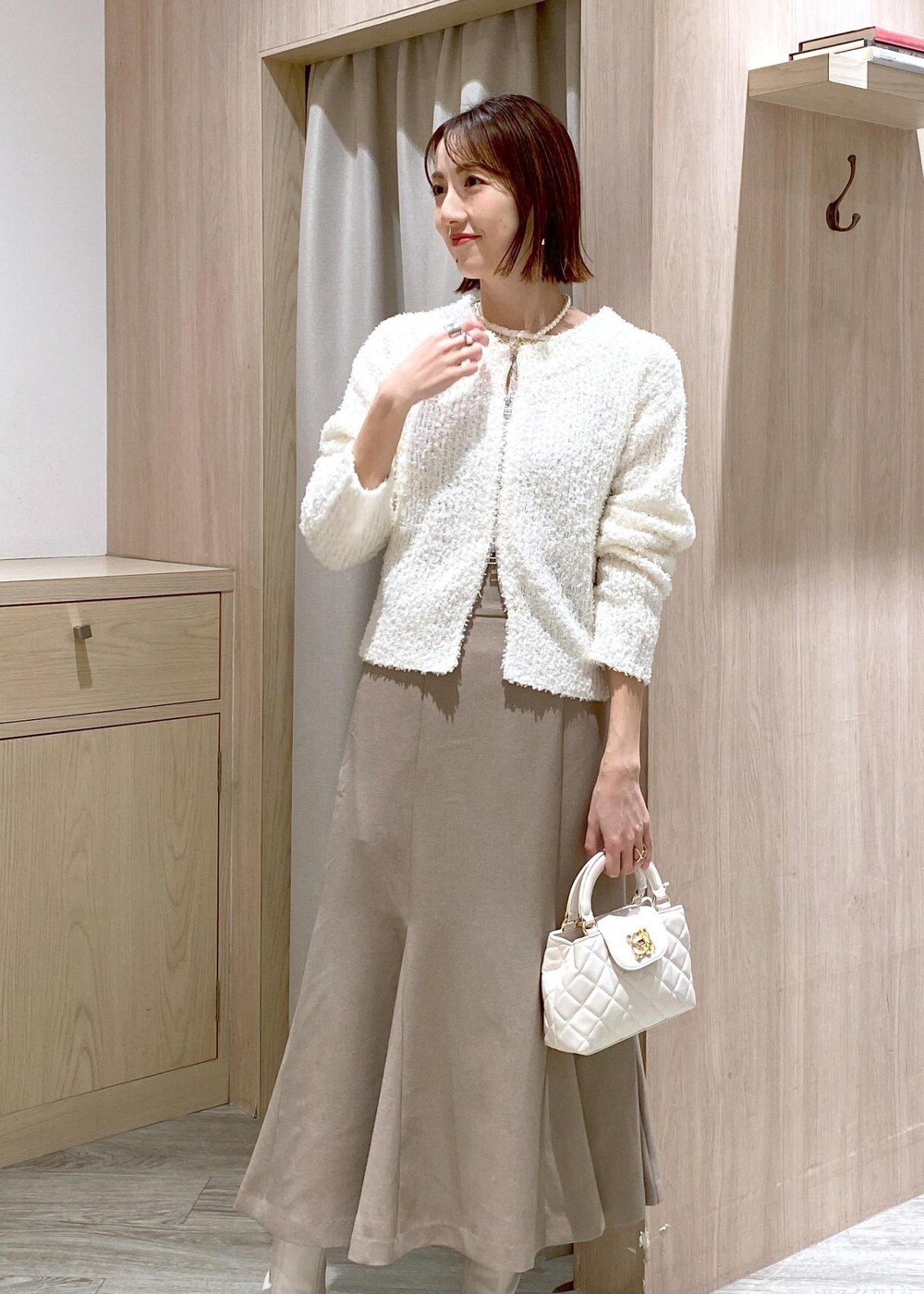 ホワイト系のブーツ、ベージュ系のスカート、ホワイト系のカーディガン/ボレロを着用したレディースの冬コーディネートの6枚目の写真