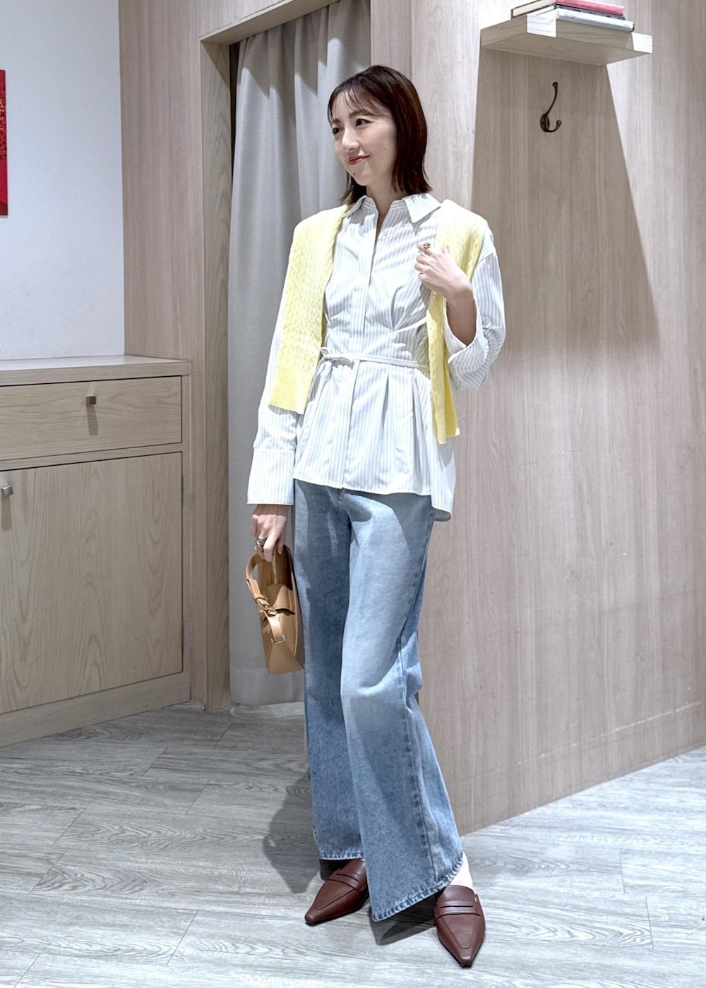 ブルー系のデニムパンツ、イエロー系のショルダーバッグ、ベージュ系のシャツ/ブラウスを着用したレディースの春コーディネートの2枚目の写真