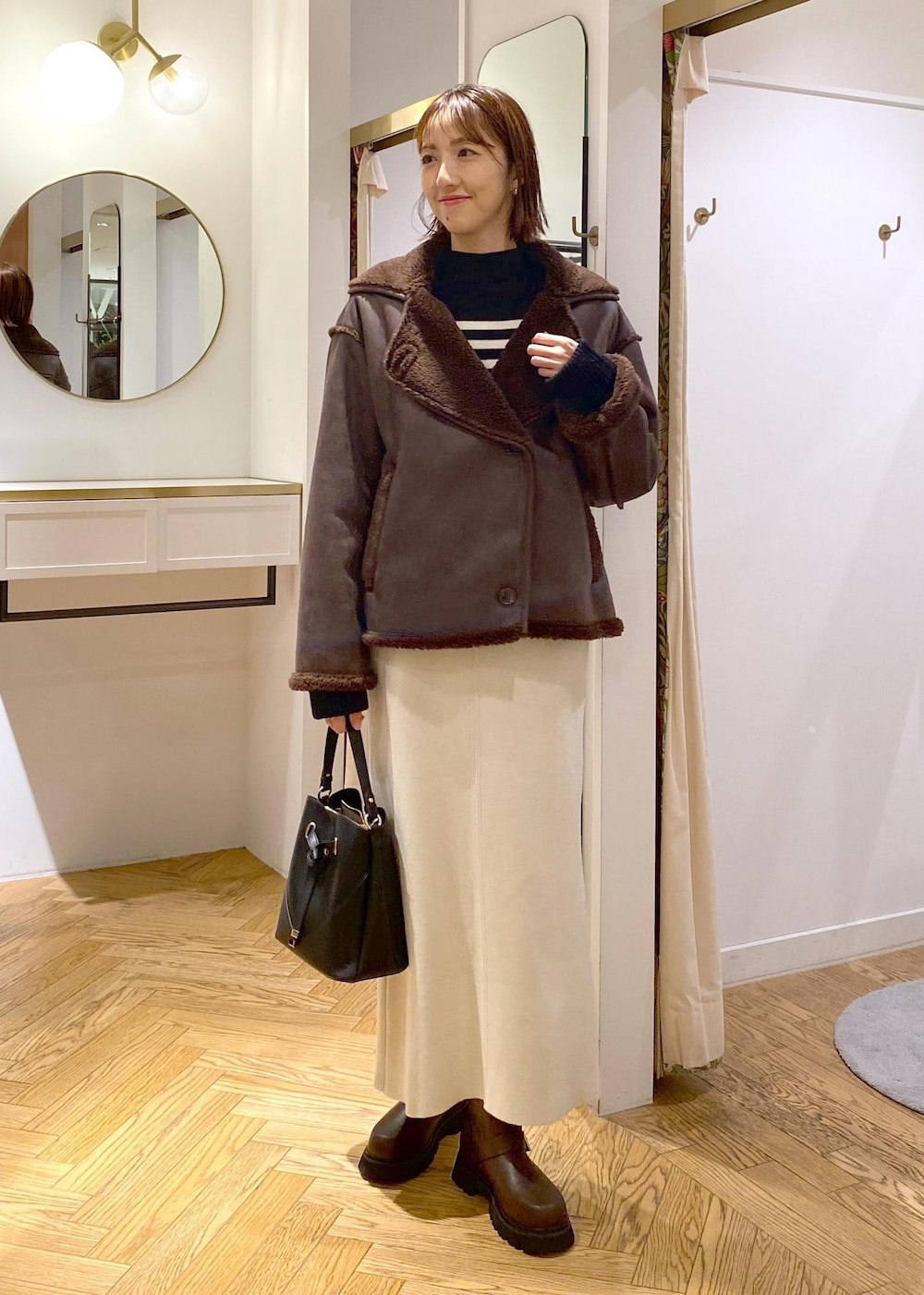 ブラック系のショルダーバッグ、ブラウン系のブーツ、ブラック系のニット/セーターを着用したレディースの秋コーディネートの3枚目の写真