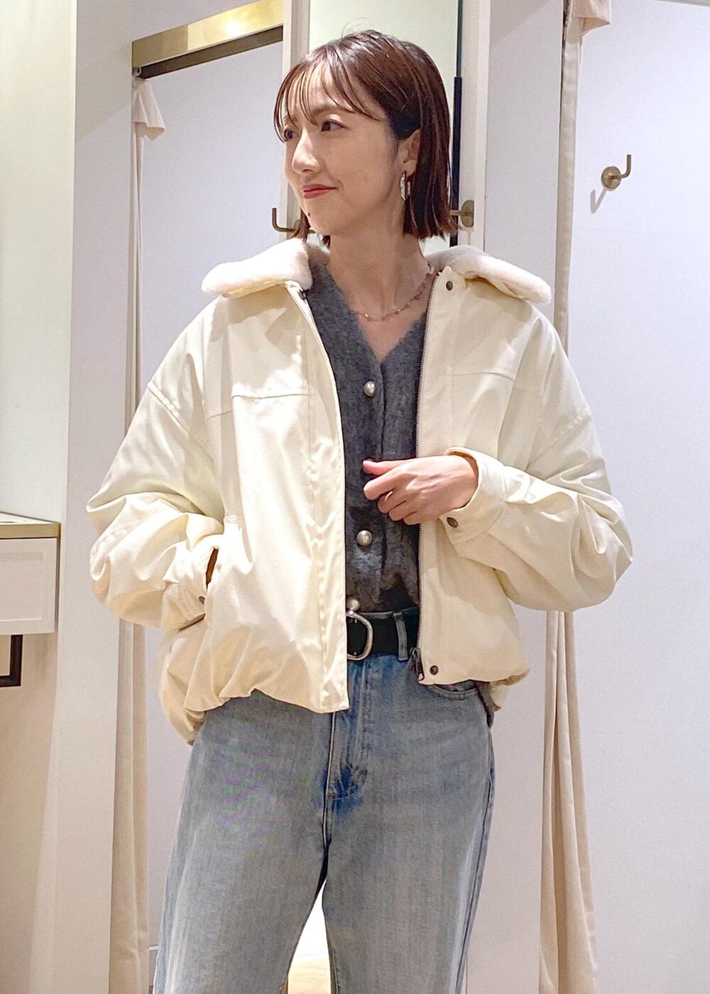 シルバー系のショルダーバッグ、ブルー系のデニムパンツ、グレー系のカーディガン/ボレロを着用したレディースの冬コーディネートの7枚目の写真