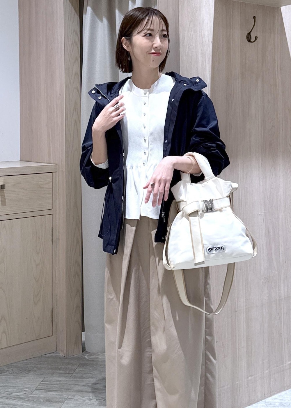ホワイト系のカーディガン/ボレロ、ホワイト系のトートバッグ、ブルー系のナイロンジャケットを着用したレディースの春コーディネートの3枚目の写真