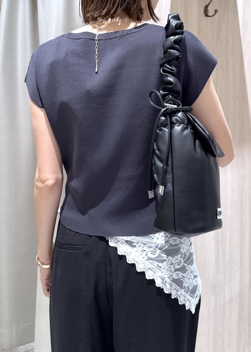 ブラック系のショルダーバッグ、ブラック系のパンプス、グレー系のニット/セーターを着用したレディースの夏コーディネートの6枚目の写真