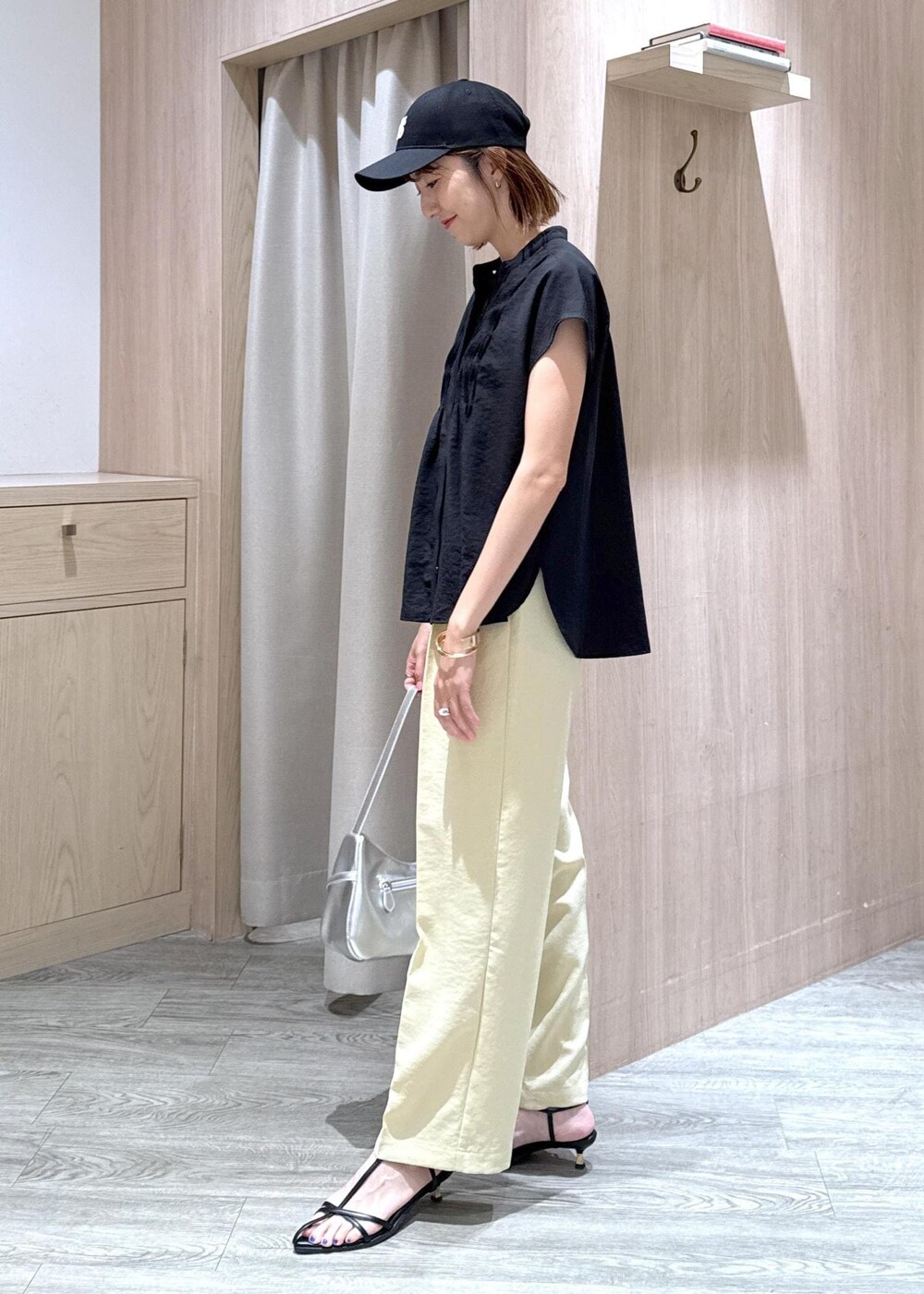 ブラック系のサンダル、イエロー系のスラックス、ブラック系のシャツ/ブラウスを着用したレディースの夏コーディネートの3枚目の写真