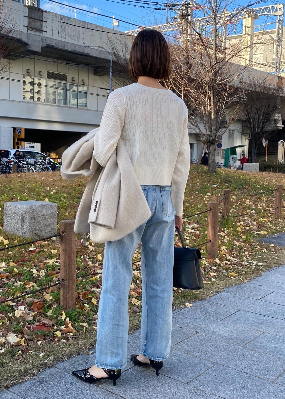 ブラック系のパンプス、ホワイト系のカーディガン/ボレロ、ベージュ系のその他アウターを着用したレディースの冬コーディネートの3枚目の写真