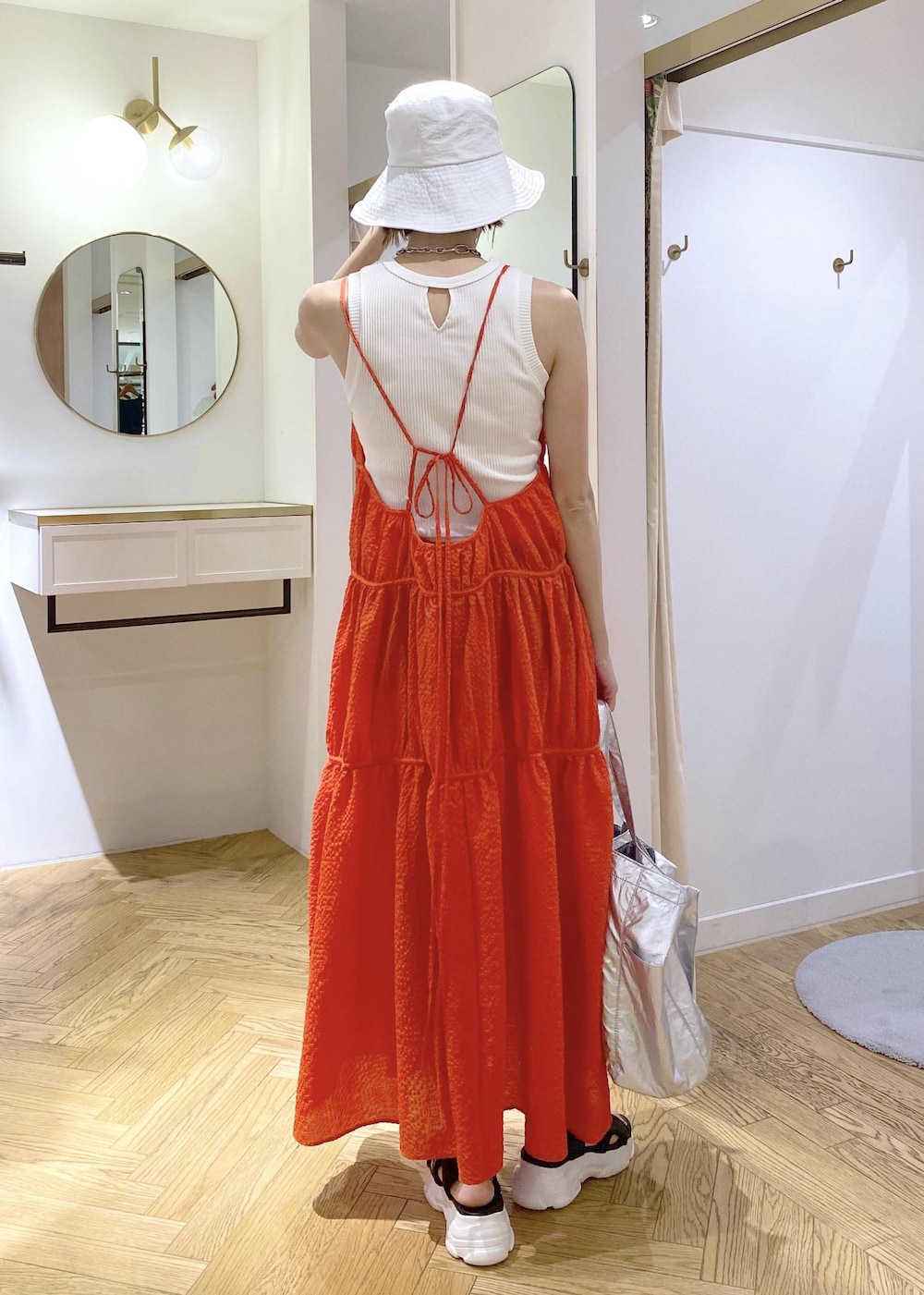 ブラック系のサンダル、オレンジ系のジャンパースカート、ホワイト系のタンクトップを着用したレディースの春コーディネートの3枚目の写真