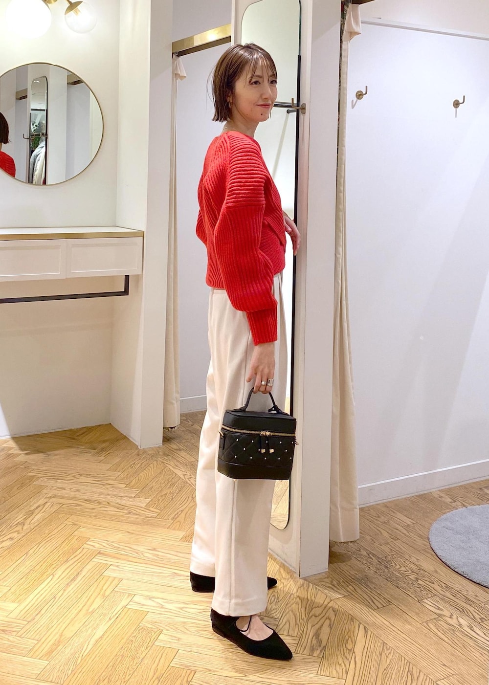 レッド系のニット/セーター、ホワイト系のスラックス、ブラック系のハンドバッグを着用したレディースの冬コーディネートの2枚目の写真