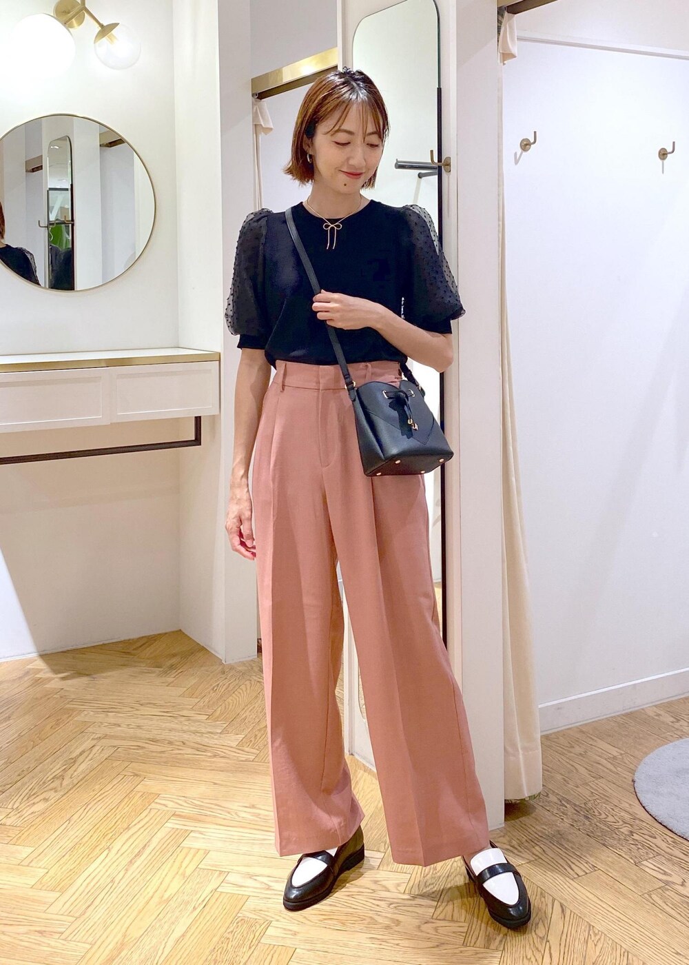 ブラック系のローファー、ブラック系のニット/セーター、ピンク系のスラックスを着用したレディースの夏コーディネートの2枚目の写真