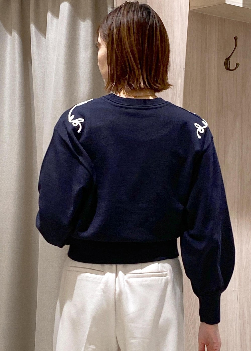 ブラック系のパンプス、ブルー系のニット/セーター、ホワイト系のスラックスを着用したレディースの冬コーディネートの8枚目の写真