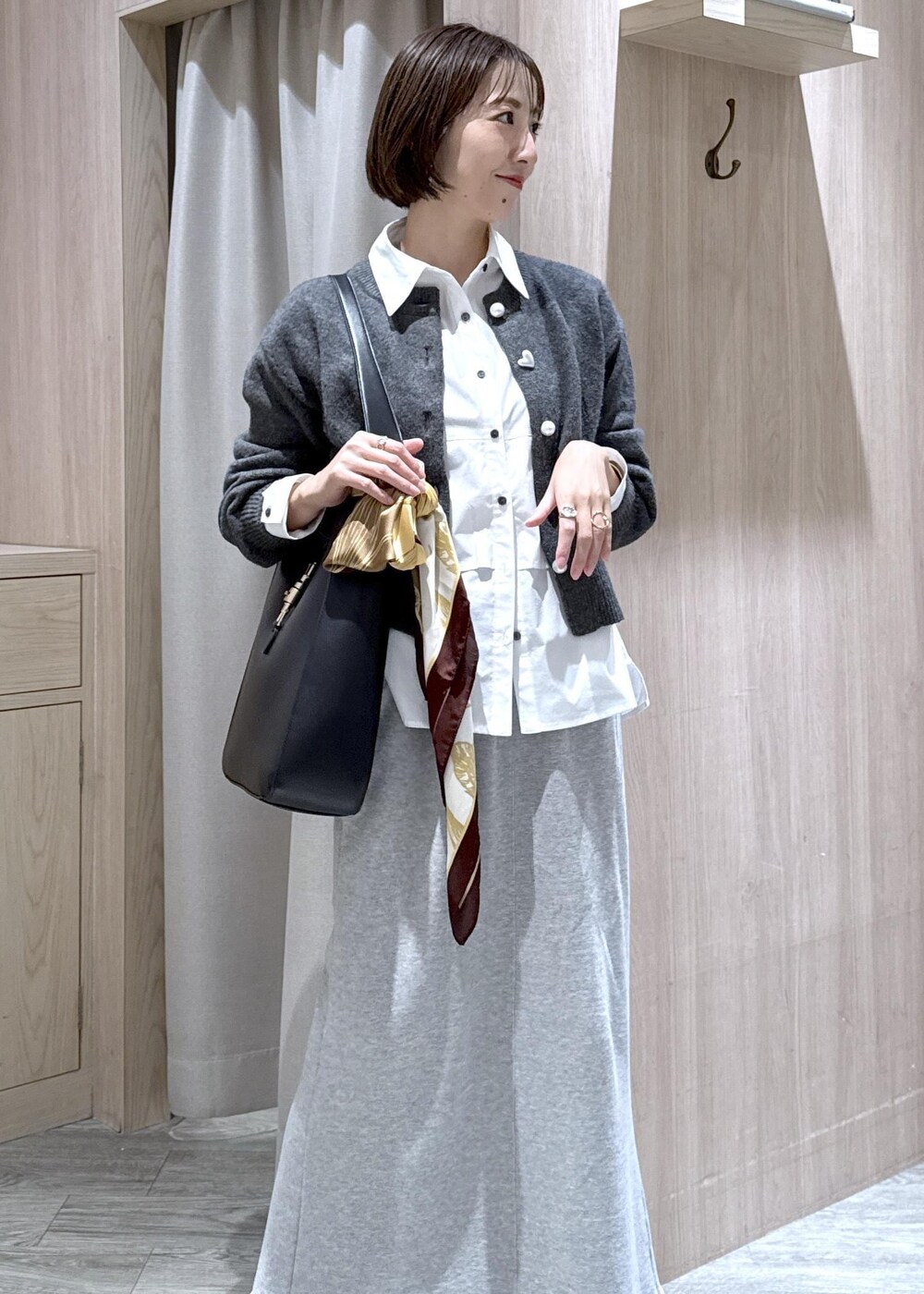 ブラック系のトートバッグ、グレー系のスカート、ホワイト系のシャツ/ブラウスを着用したレディースの秋コーディネートの6枚目の写真