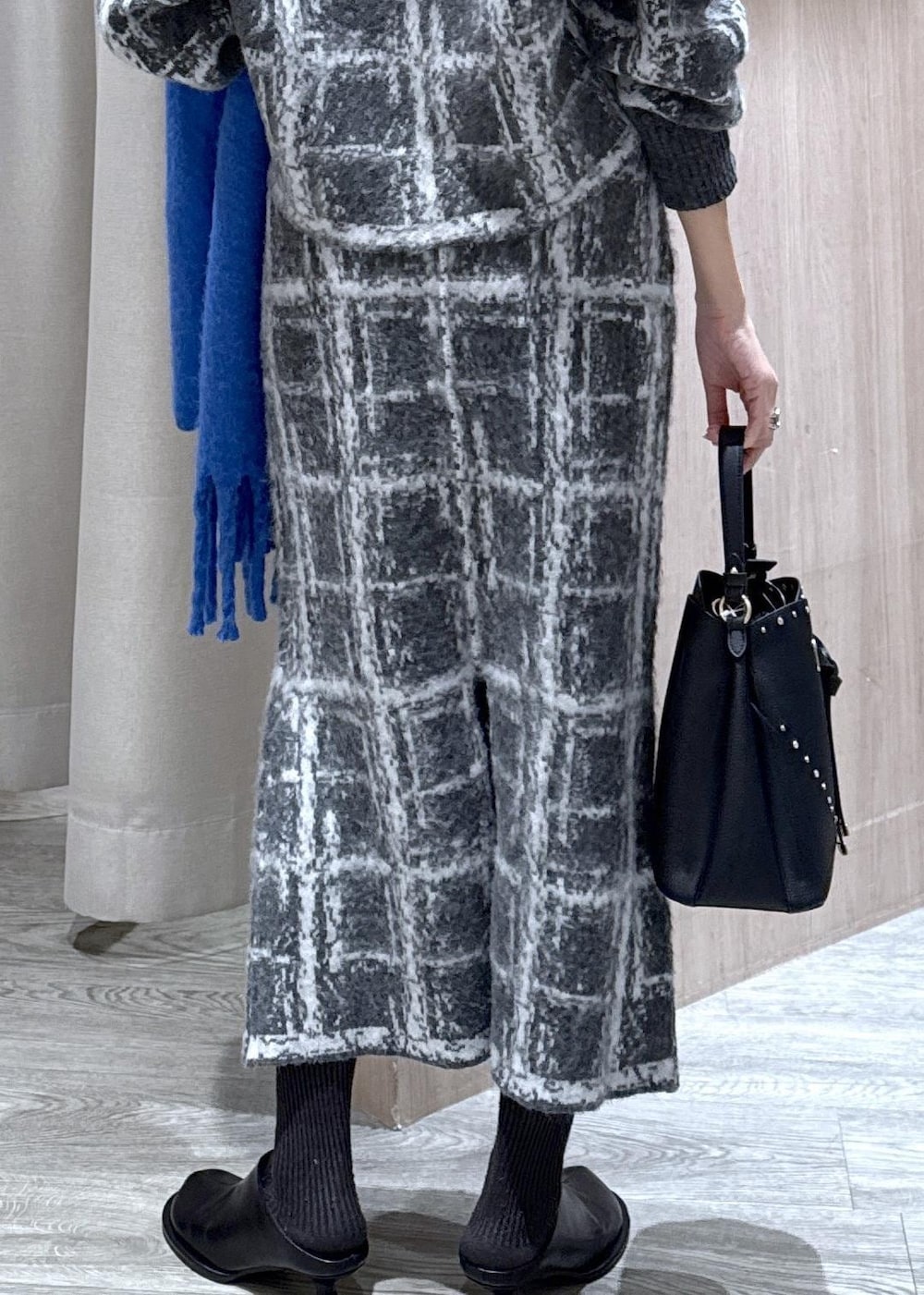 グレー系のスカート、グレー系のカーディガン/ボレロ、ブラック系のショルダーバッグを着用したレディースの冬コーディネートの8枚目の写真