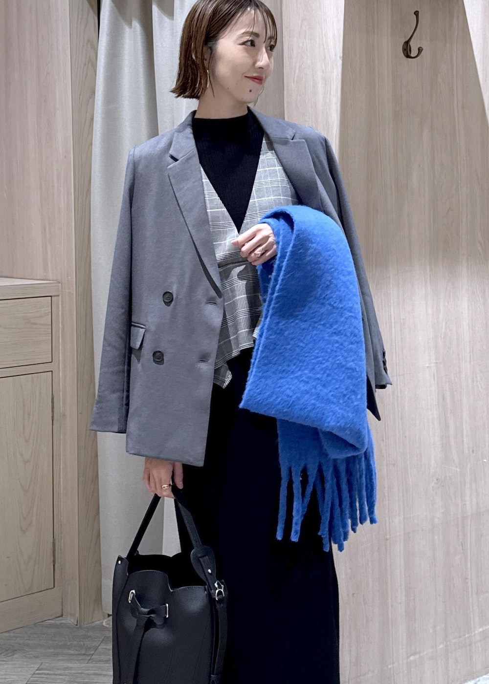 グレー系のテーラードジャケット、ブラック系のショルダーバッグ、ブラック系のワンピースを着用したレディースの冬コーディネートの2枚目の写真