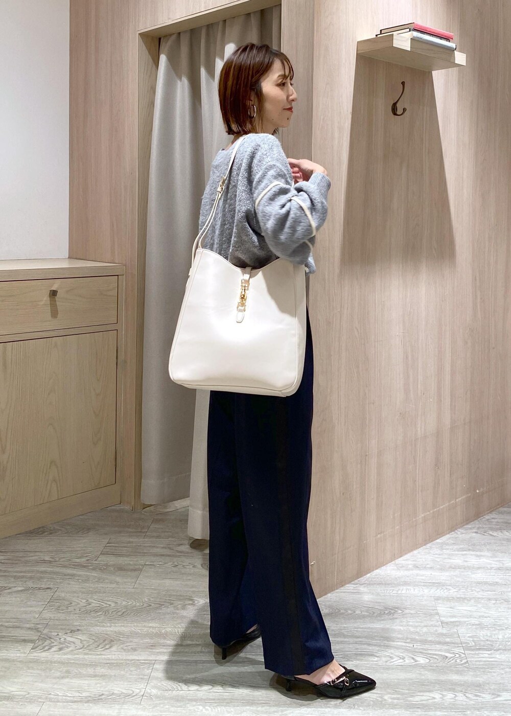 ブラック系のパンプス、グレー系のニット/セーター、ホワイト系のトートバッグを着用したレディースの冬コーディネートの3枚目の写真