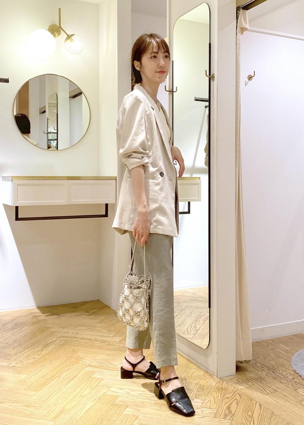 ホワイト系のタンクトップ、ブラック系のサンダル、グリーン系のスラックスを着用したレディースの春コーディネートの2枚目の写真