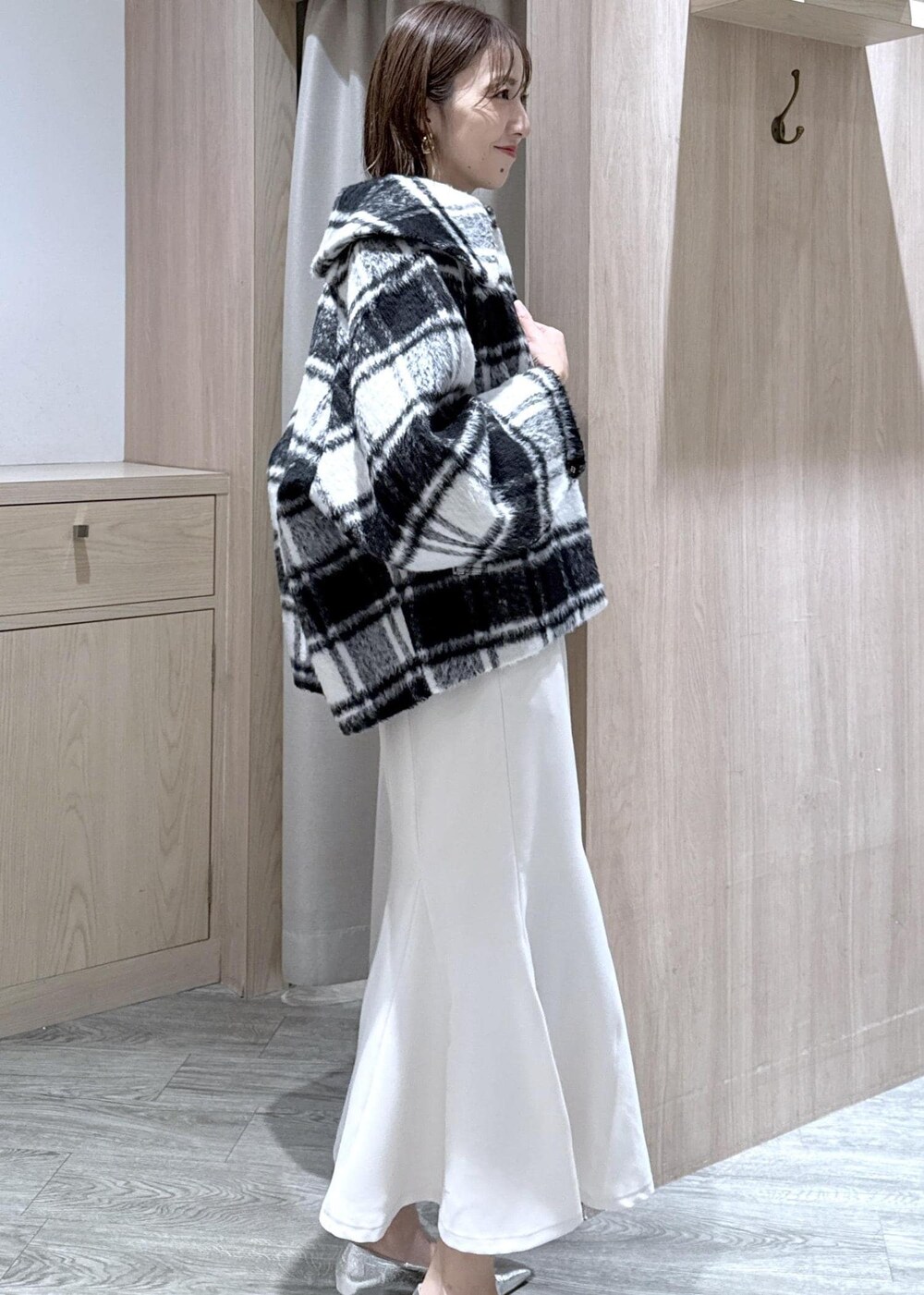 シルバー系のパンプス、ホワイト系のハンドバッグ、ブルー系のニット/セーターを着用したレディースの秋コーディネートの8枚目の写真