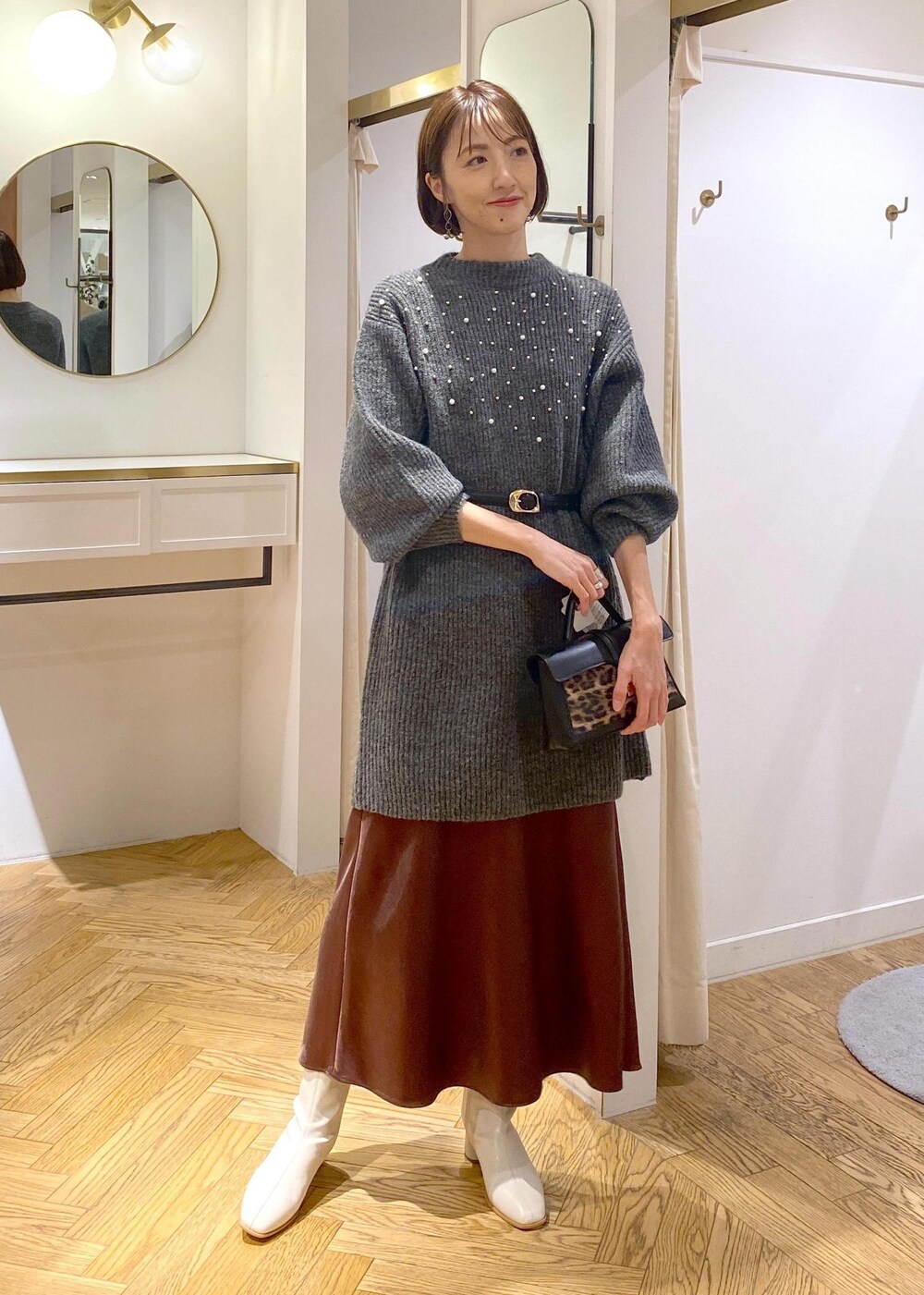 ホワイト系のブーツ、ブラウン系のスカート、グレー系のワンピースを着用したレディースの冬コーディネートの4枚目の写真