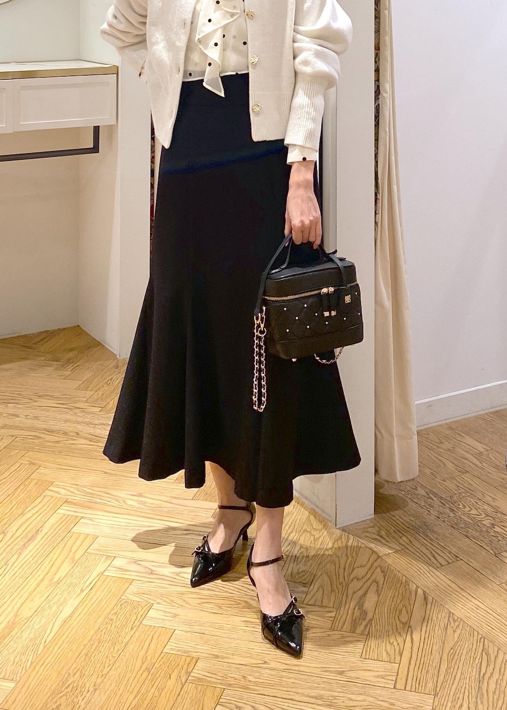 ホワイト系のカーディガン/ボレロ、ブラック系のスカート、ブラック系のパンプスを着用したレディースの冬コーディネートの5枚目の写真