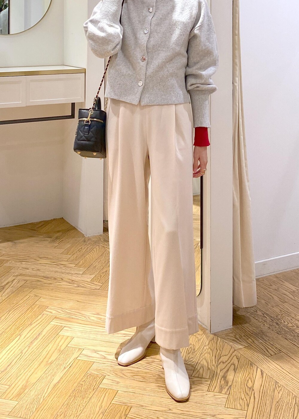 ホワイト系のブーツ、グレー系のカーディガン/ボレロ、レッド系のニット/セーターを着用したレディースの冬コーディネートの5枚目の写真