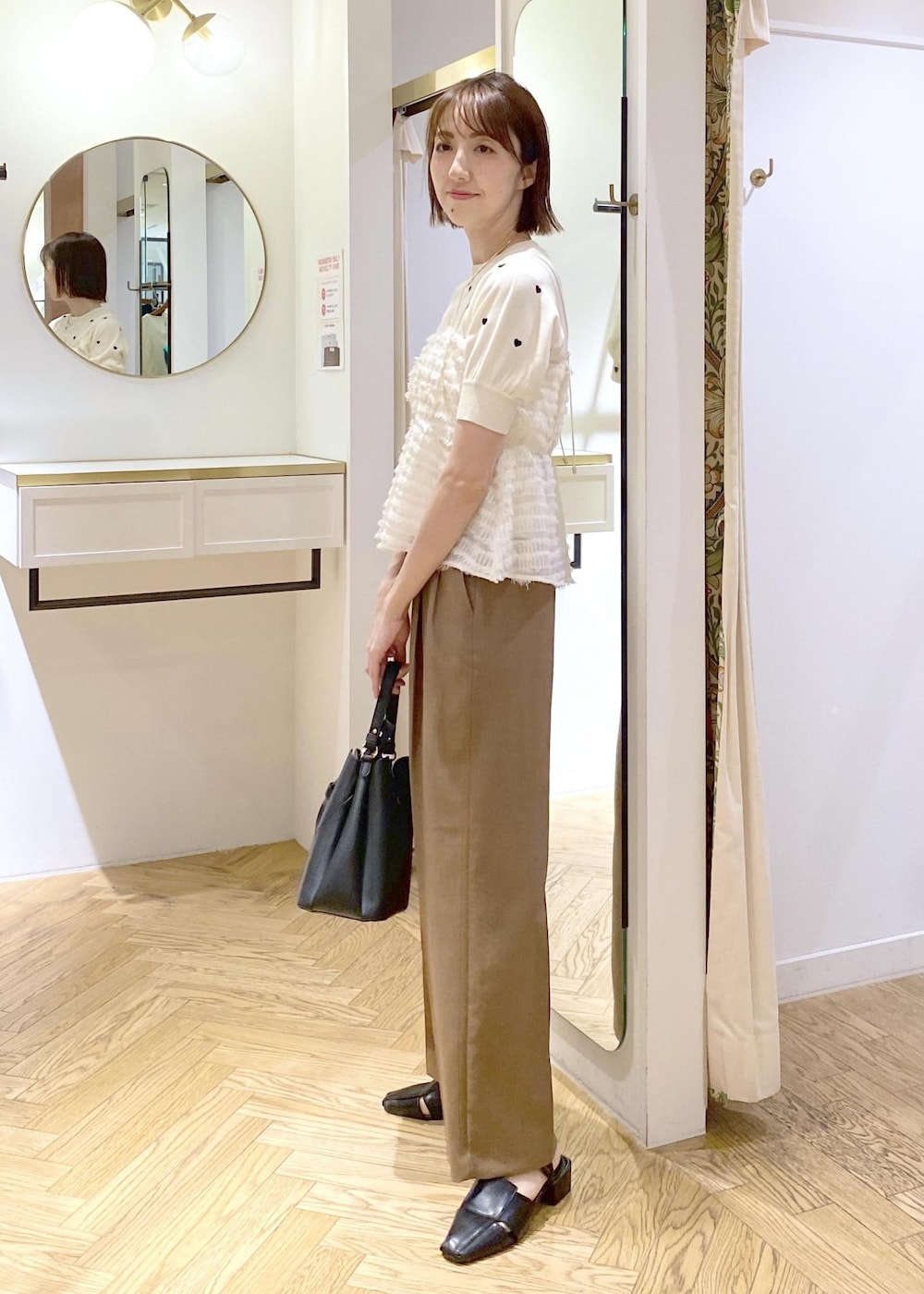 ブラック系のサンダル、ブラック系のハンドバッグ、ホワイト系のニット/セーターを着用したレディースの春コーディネートの2枚目の写真