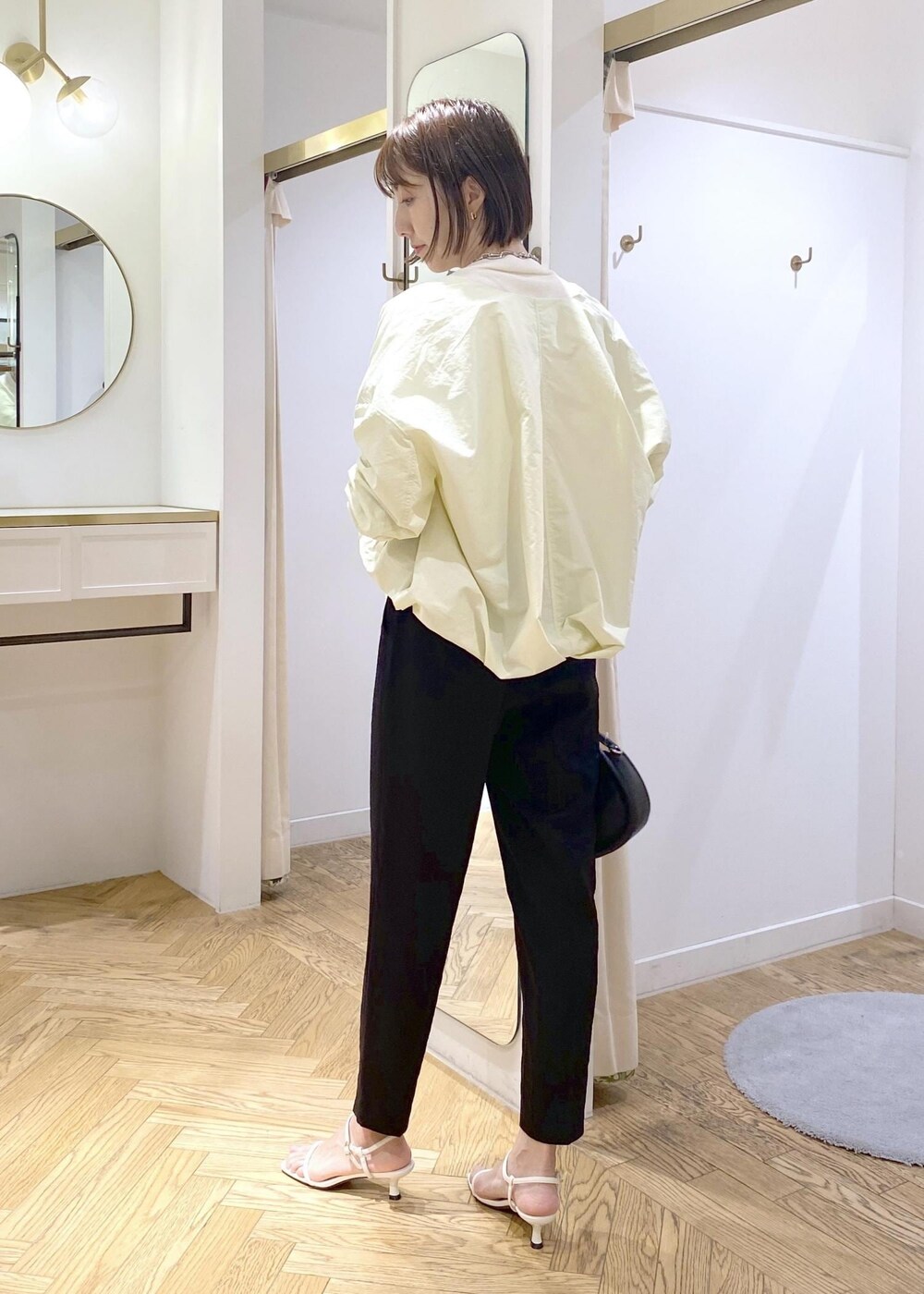 ブラック系のショルダーバッグ、ホワイト系のキャミソール、ブラック系のスラックスを着用したレディースの春コーディネートの2枚目の写真